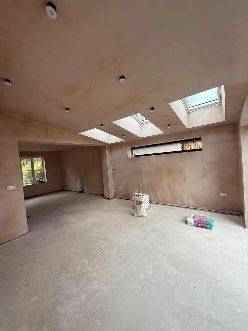 Freshly plastered open-plan extension with downlights and two roof lights, at second fix stage